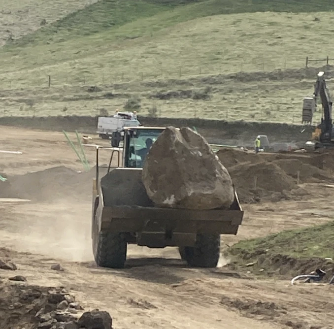 backhoe loader carrying large bolder